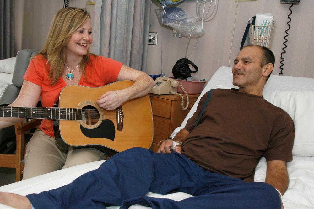  一位音乐治疗师为一位医院病人弹吉他.